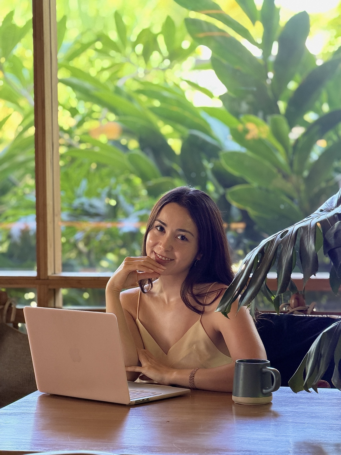 Ayaka Picard seated at a table with a laptop in a tropical setting